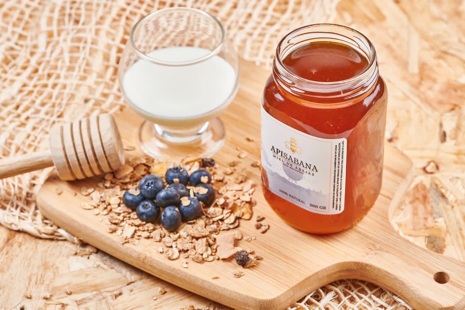 Bodegón de miel, arándanos y granola sobre tabla de bambú