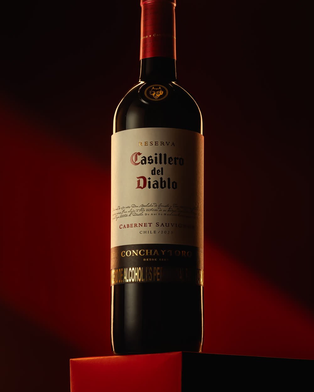 Botella de vino sobre fondo rojo con luz dirigida