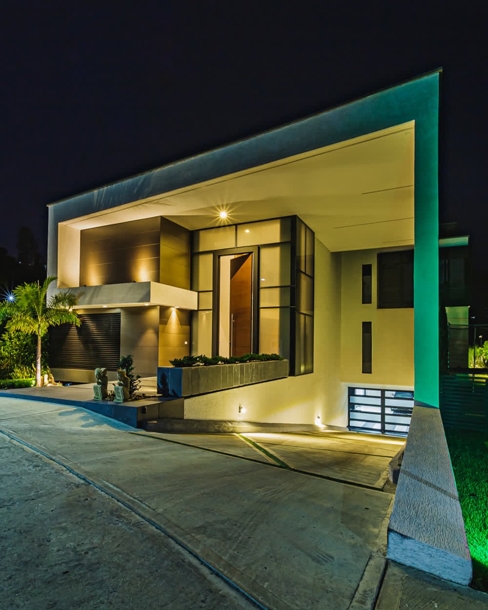 Casa moderna iluminada en hora azul, vista desde el acceso