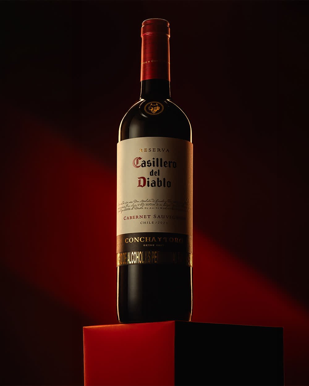 Botella de vino sobre pedestal rojo con luz dirigida